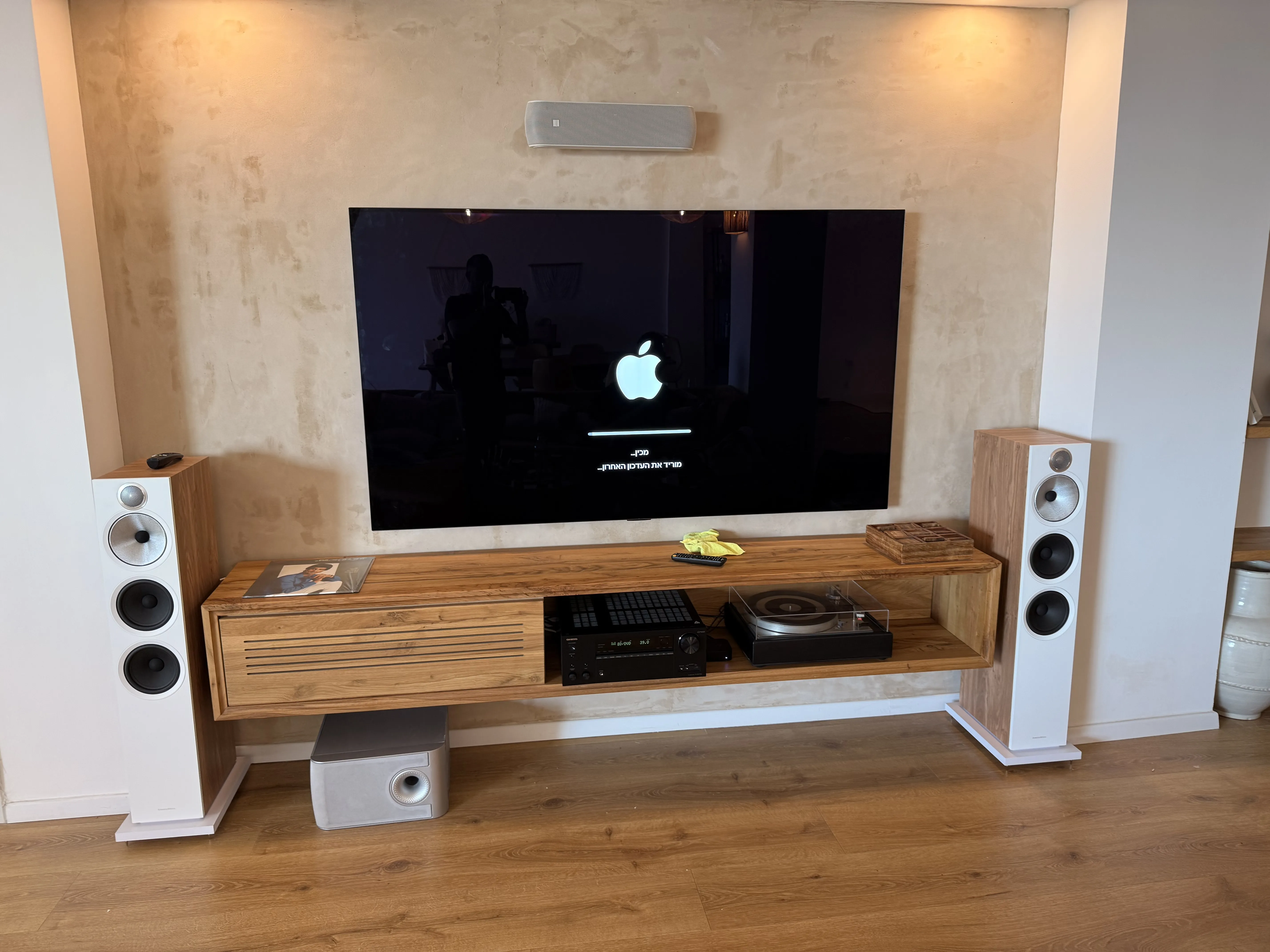 פרויקט קולנוע ביתי בסלון מודרני עם רמקולים לבנים וקיר טקסטורי